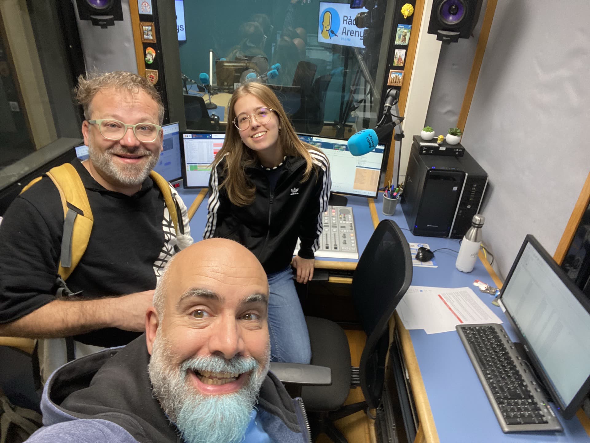 Selfi de David Herrero, Jordi Anglada y Marina Cabrera en el control de sonido del estudio 1 de Ràdio Arenys, con el micrófono azul y el rótulo de la emisora al fondo